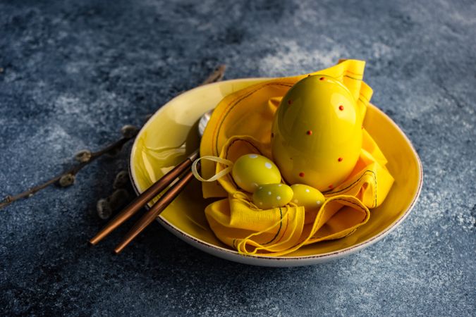 Easter table setting with yellow egg ornaments in yellow bowl