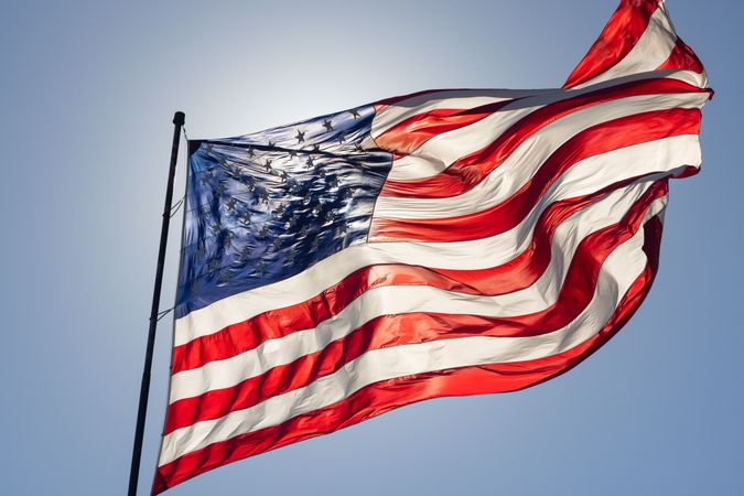 Backlit American Flag Waving In Wind Against a Deep Blue Sky