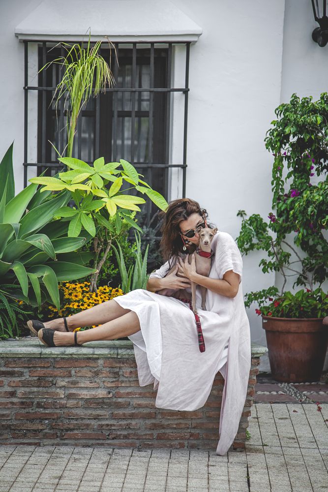 Woman kissing greyhound while relaxing on street