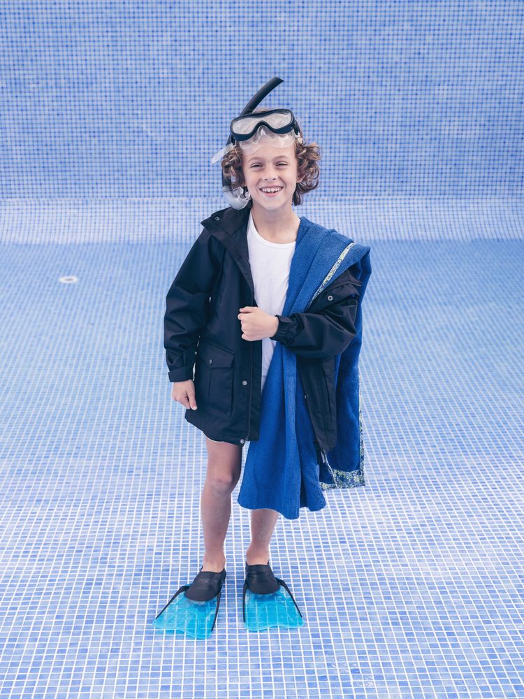 Cheerful boy in mask and flippers in empty pool