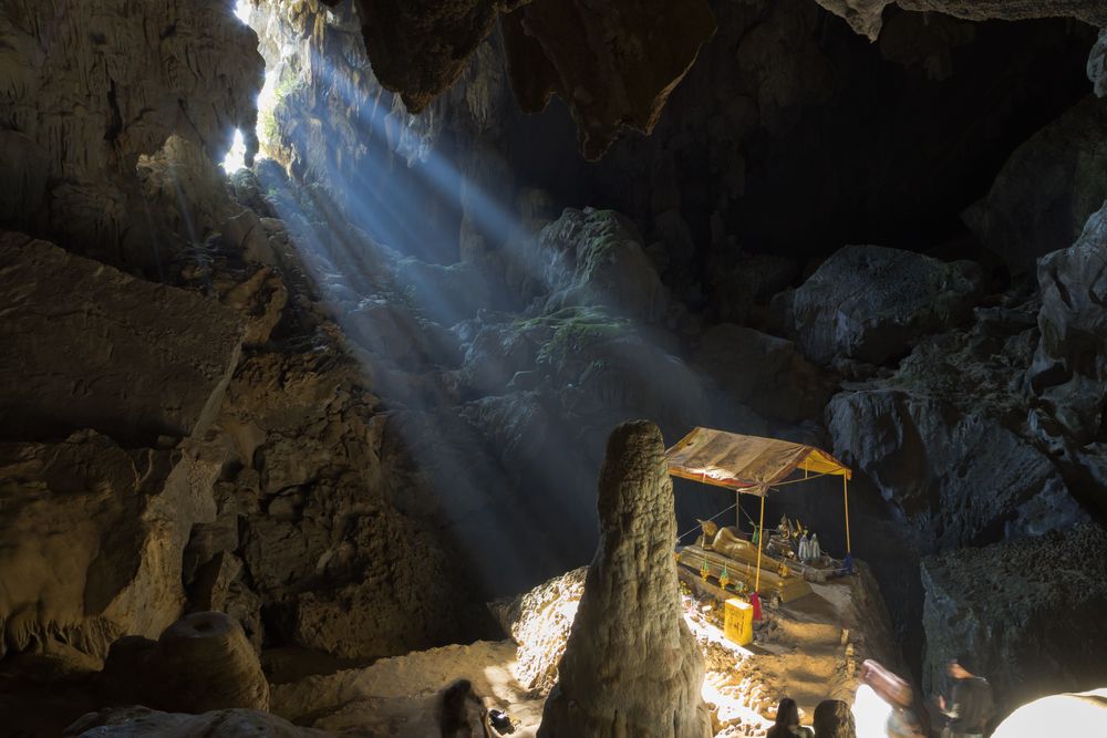 Sunrays entering the immense Phu Kham Cave, famous for its reclining golden Buddha, Laos