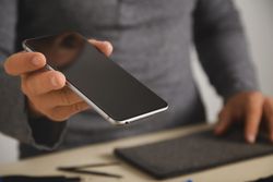 Close up of man holding smart phone in repair shop