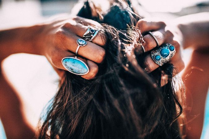 Woman wearing turquoise rings holding her hair