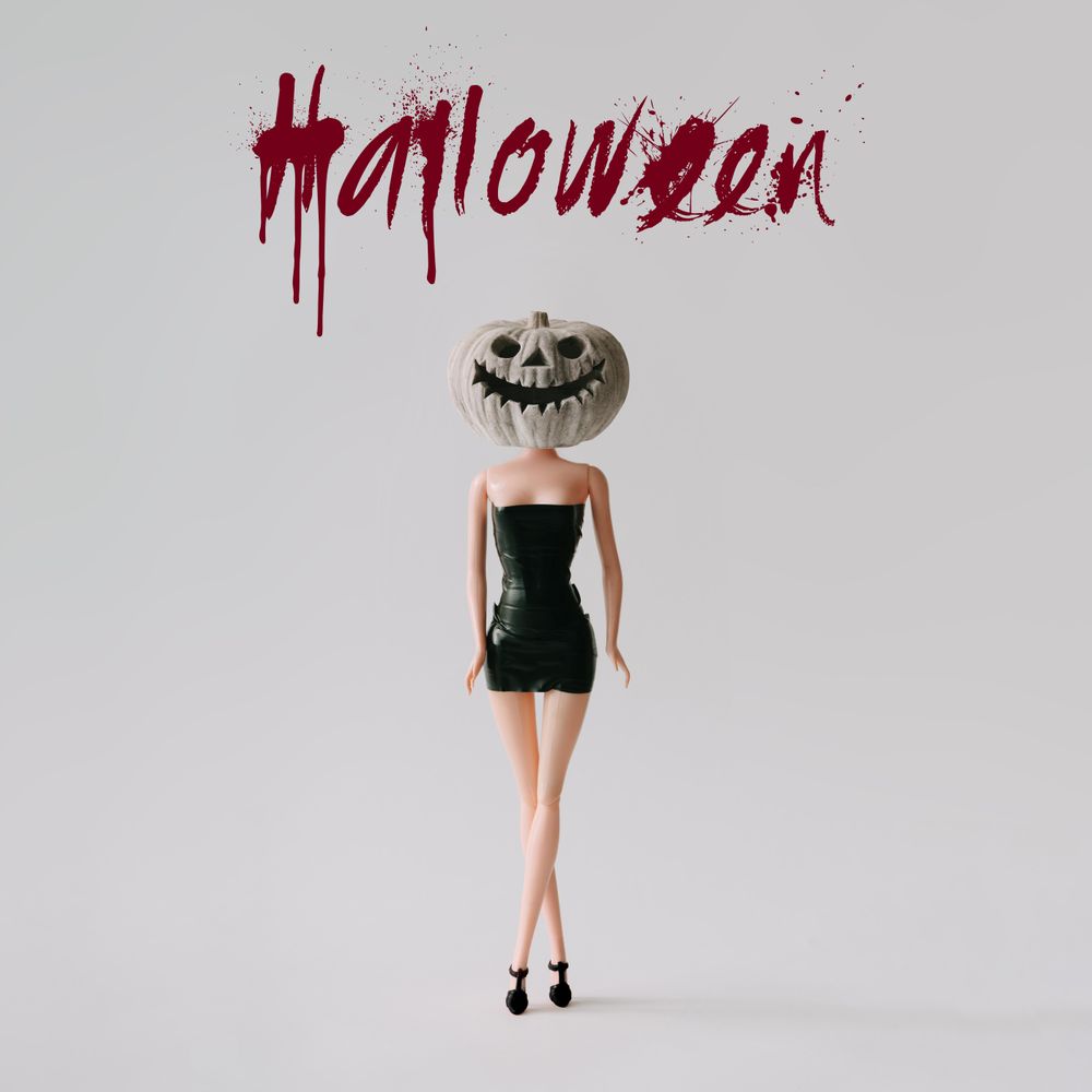 Doll in dress with skull pumpkin head with “Halloween” text