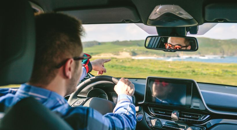 Young man holding steering and pointing driving