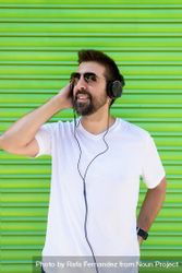 Man in headphones and glasses in front of green background 4MXmE5