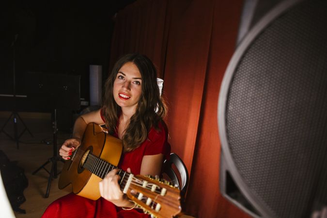 Creative woman singing and playing guitar on stage