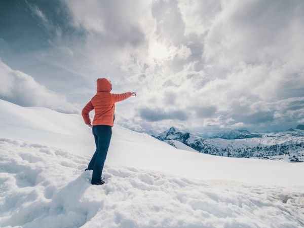 Unrecognizable lonely traveler walking on snowy hill
