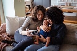 Two women with dog and baby on sofa making video call