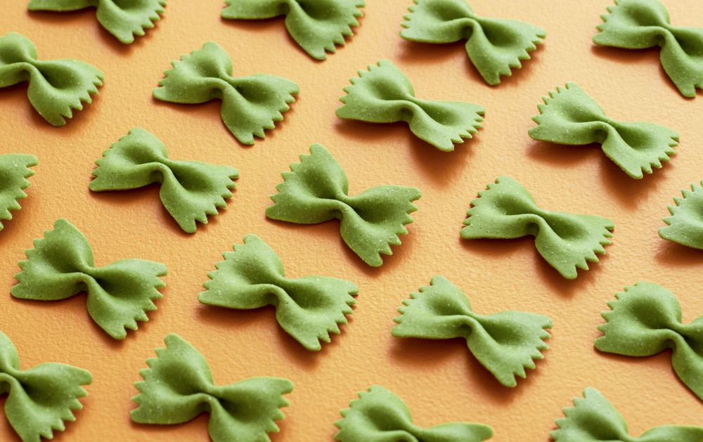 Green farfalle pasta on an orange table