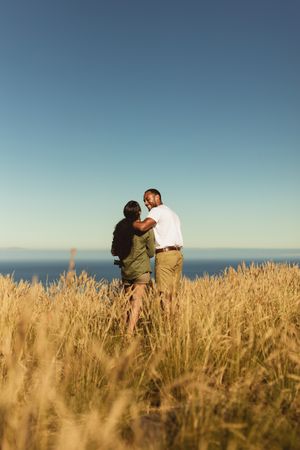 Rear view of a romantic couple standing together in a field