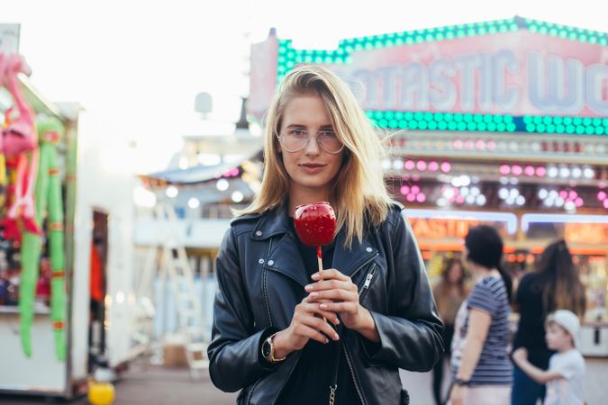 Stylish woman with a serious expression holding a candied apple