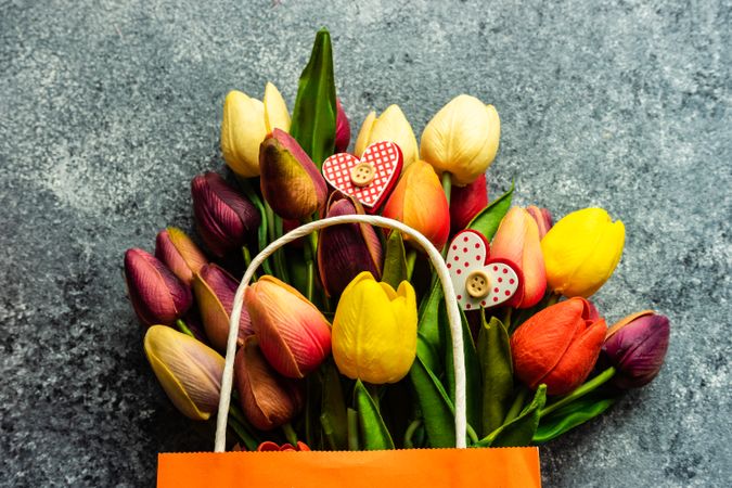 Valentine's day concept with heart shaped ornaments scattered on fresh tulips on grey counter