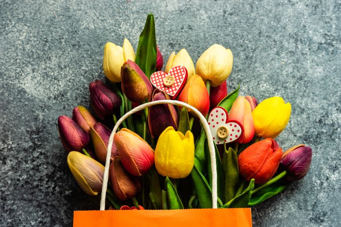 Valentine's day concept with heart shaped ornaments scattered on fresh tulips on grey counter
