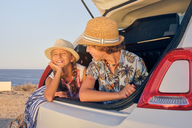 Girl inside the trunk of a car making a wait gesture with happy