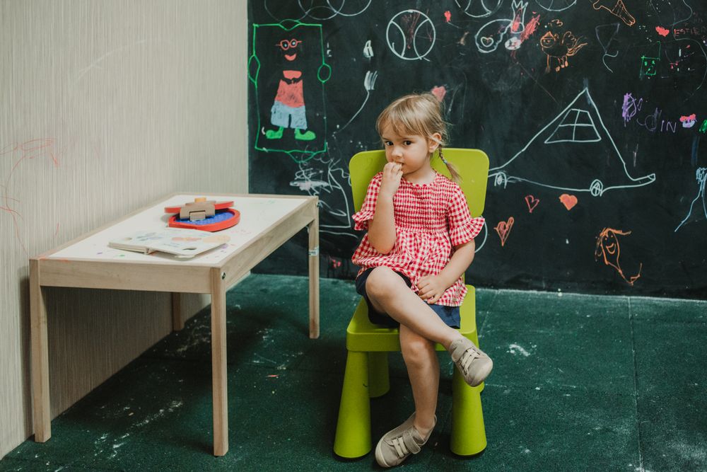 Girl sitting on light green chair with crossed legs