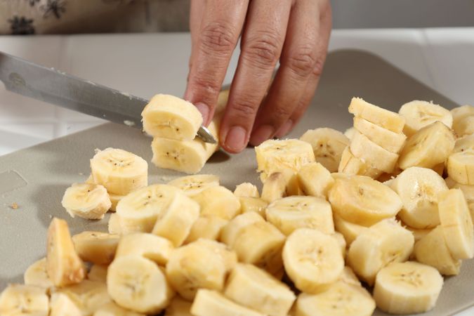 Hands of Old Female Slicing Banana
