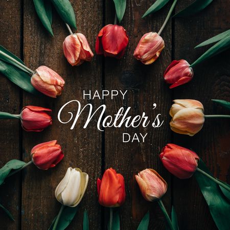 Circle of tulips on wooden background with “Happy Mother’s Day” text