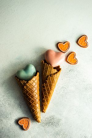 Two ceramic hearts in waffle cones on grey background sugar cookies and space for text