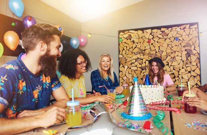 Group of friends sitting around a birthday cake on a table