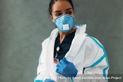 Black woman removing her hazmat suit in protective gloves and face mask 0LQZA5