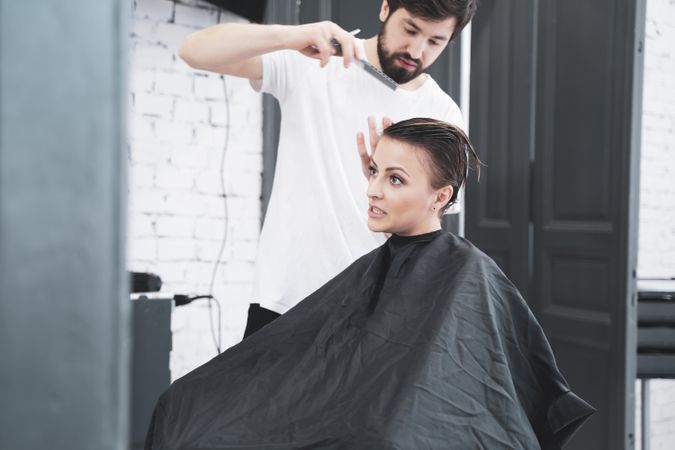 Hairdresser cuts woman's hair with scissors