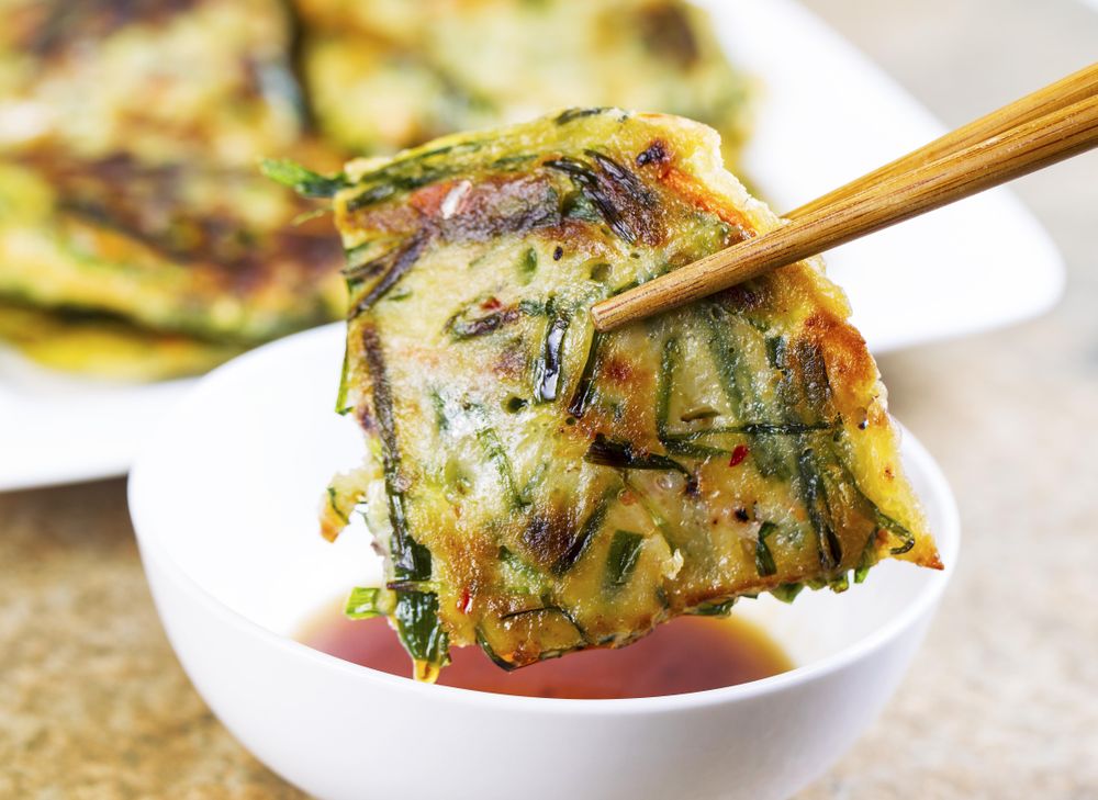 Korean green onion pancake being dipped in sauce