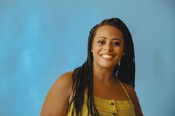 Portrait of confident smiling female with long braided hair in yellow shirt, copy space
