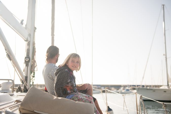 Man with child sitting on edge of yacht in sea