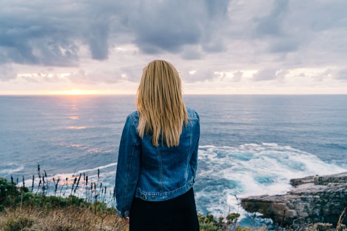 Woman on seashore against dusky clouds