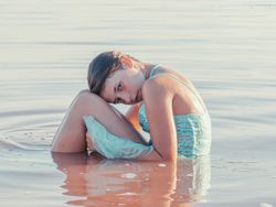 Teenage girl sitting in fresh water in sunny day