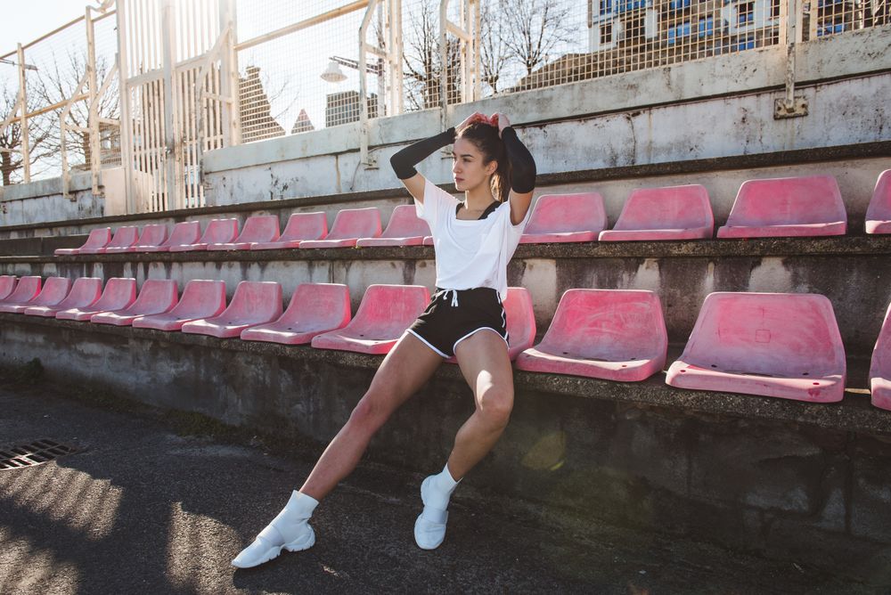 Young sportswoman resting on shabby seat