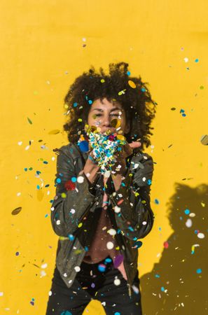 Black woman with afro hair celebrating with confetti.