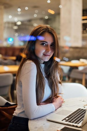 Woman looking up from laptop in a cafe