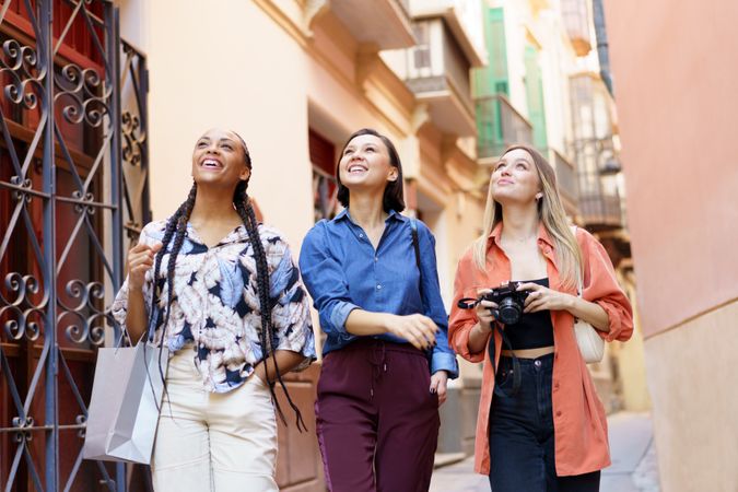 Three happy women walking down narrow lane looking up