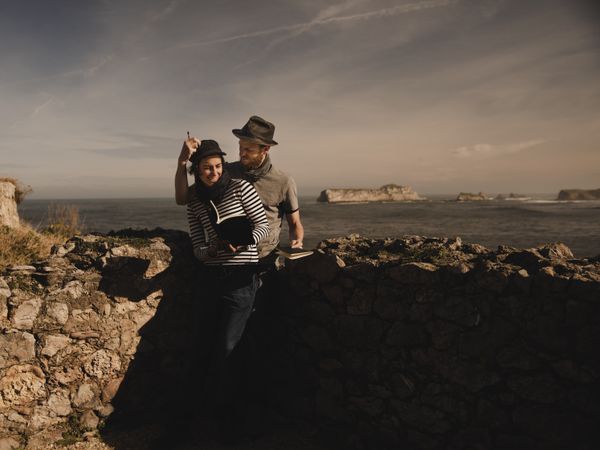 Man near woman with books near stones on shore