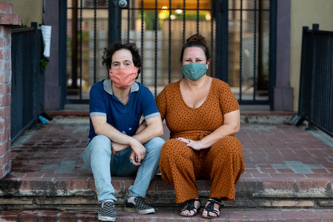 Loving couple sitting together on stoop smiling and looking at camera