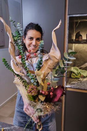 Smiling woman with composition of flowers in floristry wor