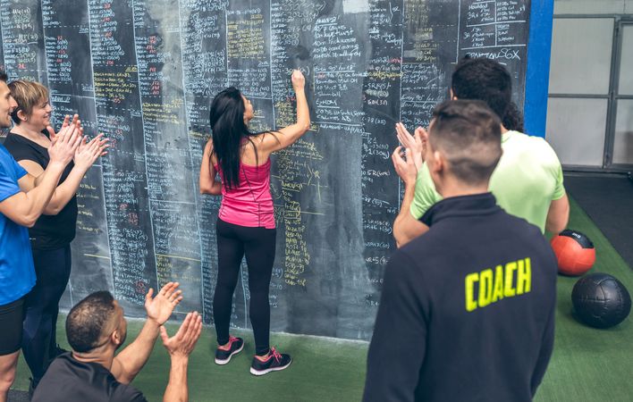 Athlete woman writing down results on the gym board