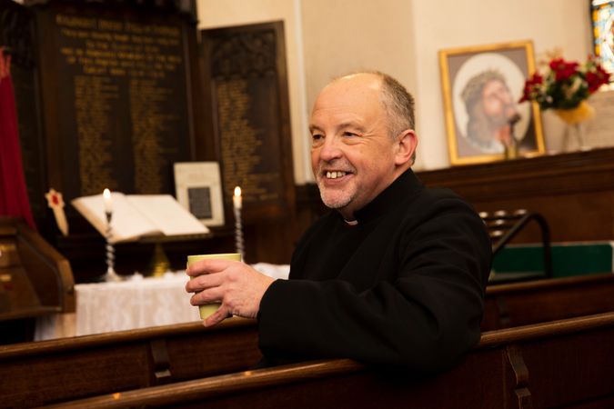 Vicar with tea in pew