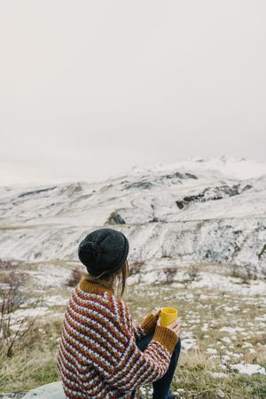 Young woman with cup between mountains