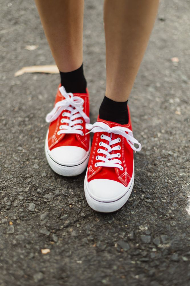 The feet of a young woman, wearing red white rubber toe shoes on the asphalt of a road