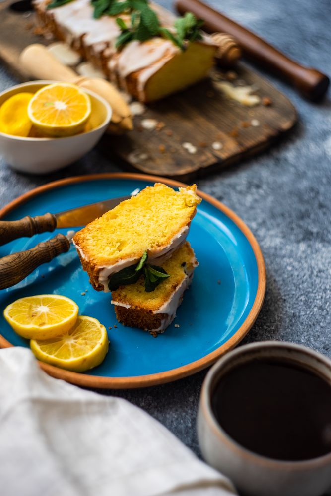 Two sliced of tasty lemon cake on blue plate