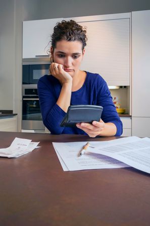 Stressed women using calculator while going through bills