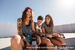 Beautiful woman sitting on ramp with friends at skate park 56eqY0