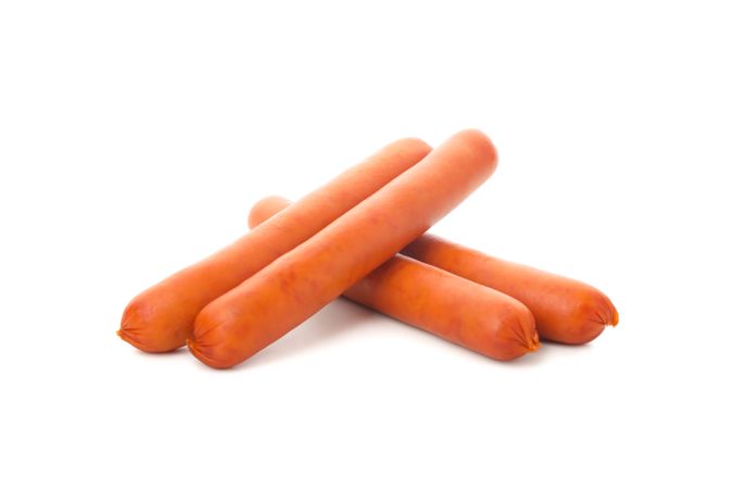 Four sausages balancing on each other on plain background