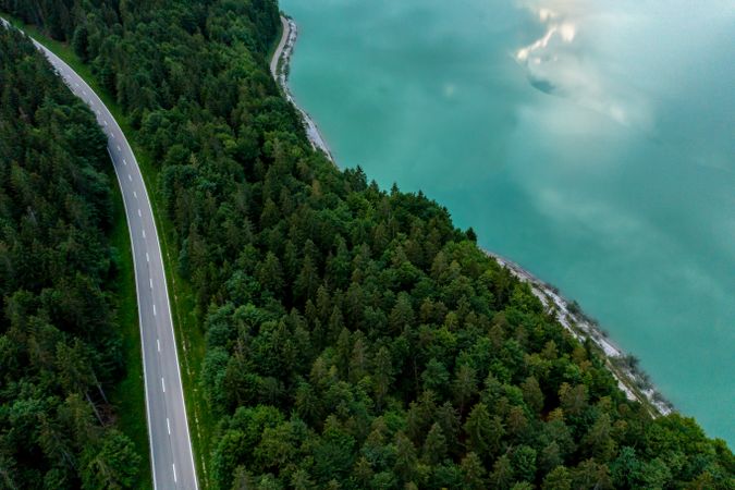 Drone aerial view of a road passing through forest on Sylvenstein lakeshore