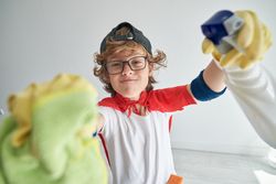 Content child in superhero costume wiping camera against white w