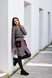 Female leaning on bright wall outside in winter coat dress