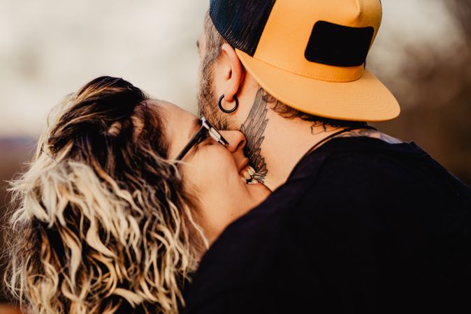 Happy couple hugging and kissing near tree in park